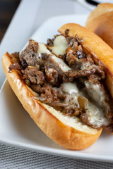 A closeup view of a philly cheesesteak sandwich, in a restaurant or kitchen setting.