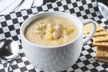 A view of a cup of New England clam chowder, in a restaurant or kitchen setting.