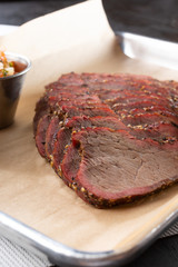 A closeup view of a tray of barbecue tri tip meat slices, in a restaurant or kitchen setting.