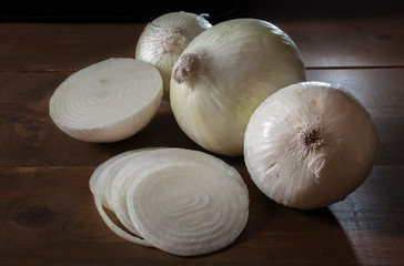 still life photography, Group of white onions and slices on a table as part of dark food photography, close up or macro photography or low key light photography.