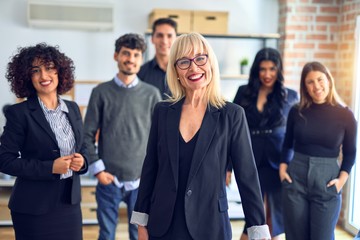 Group of business workers smiling happy and confident. Posing together looking at the camera, middle age beautiful woman with smile on face at the office