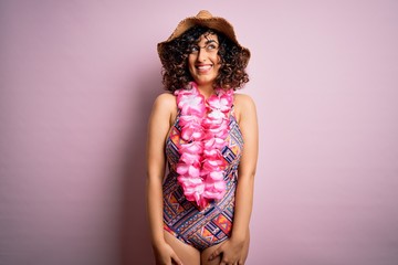 Young beautiful arab woman on vacation wearing swimsuit and hawaiian lei flowers smiling looking to the side and staring away thinking.