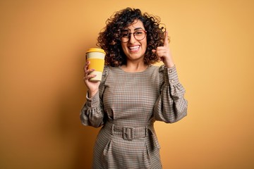Young beautiful curly arab businesswoman wearing glasses drinking cup of takeaway coffe surprised with an idea or question pointing finger with happy face, number one