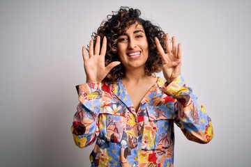 Young beautiful curly arab woman wearing floral colorful shirt standing over white background...