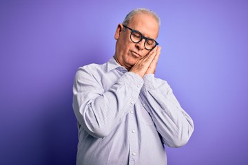 Obraz premium Middle age handsome hoary man wearing striped shirt and glasses over purple background sleeping tired dreaming and posing with hands together while smiling with closed eyes.