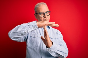 Middle age handsome hoary man wearing casual striped shirt and glasses over red background Doing...