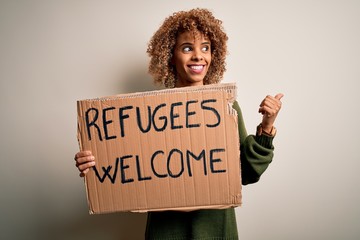 African american woman asking for immigration holding banner with wlecome refugees message pointing...