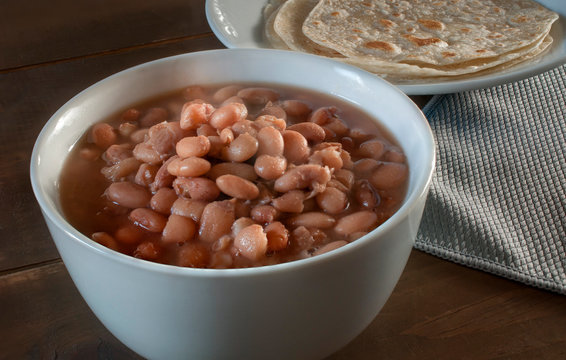 Mexican food frijoles de la olla and flour tortillas on a rustic table 