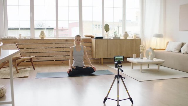 Attractive Caucasian recording making live stream or vlog about doing yoga at home. Stay home, quarantine workout. Shot on ARRI Alexa Mini with Cooke S4 lenses
