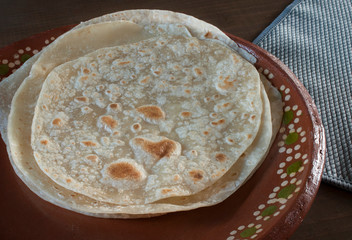 flour tortillas on a clay Mexican plate or mud plate with a blue napkin on the side with rim light 