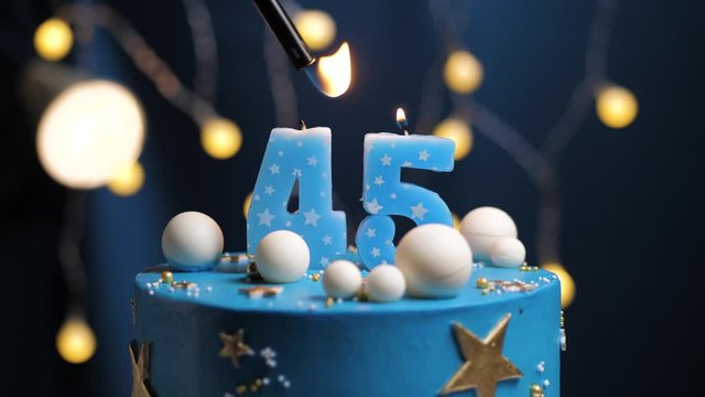 Birthday cake number 45 stars sky and moon concept, blue candle is fire by lighter and then blows out. Copy space on right side of screen if required. Close-up and slow motion