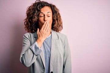 Middle age beautiful businesswoman wearing elegant jacket over isolated pink background bored yawning tired covering mouth with hand. Restless and sleepiness.