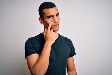 Young handsome african american man wearing casual t-shirt standing over white background Pointing to the eye watching you gesture, suspicious expression