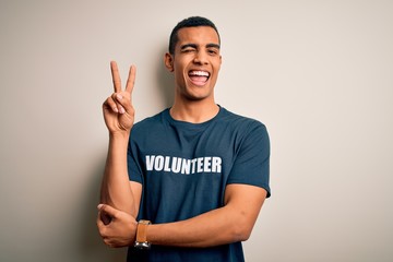 Young handsome african american man volunteering wearing t-shirt with volunteer message smiling...