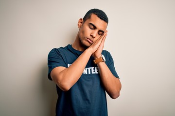 Young handsome african american man volunteering wearing t-shirt with volunteer message sleeping...