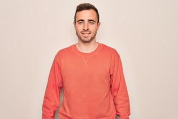 Young handsome man with blue eyes wearing casual sweater standing over white background with a happy and cool smile on face. Lucky person.