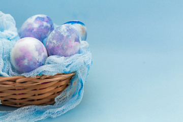 Easter basket with colorful cosmic eggs close-up on a blue background. Happy Easter card with copy space for text.