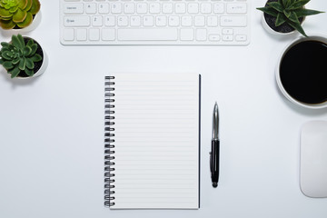Top view from above of Blank notebook with keyboard, mouse and cup coffee on white table background. Workplace for creative work of designer. Flat lay, Business-finance concept with copy space.