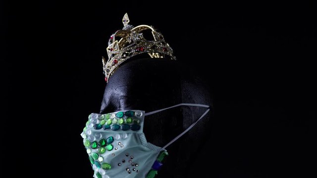 Doll head wearing medical urban luxury gem protective mask and gold crown. Fashion creative design trend during virus disease, COVID 19  coronavirus pandemic and self isolation quarantine.