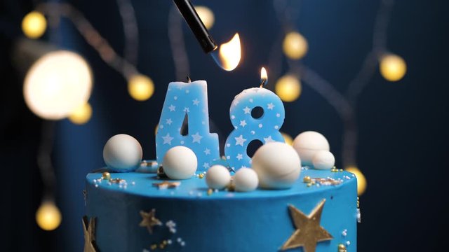 Birthday cake number 48 stars sky and moon concept, blue candle is fire by lighter and then blows out. Copy space on right side of screen if required. Close-up and slow motion