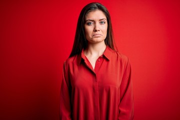 Fototapeta premium Young beautiful woman with blue eyes wearing casual shirt standing over red background depressed and worry for distress, crying angry and afraid. Sad expression.