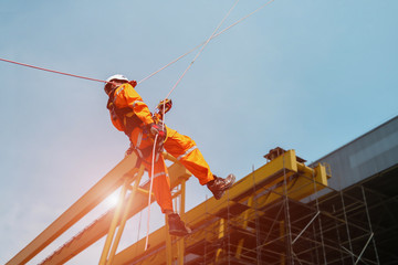 Worker Demonstration or rope access the Abseiling of high place wearing equipment protective PPE with full safety harness in construction site - obrazy, fototapety, plakaty