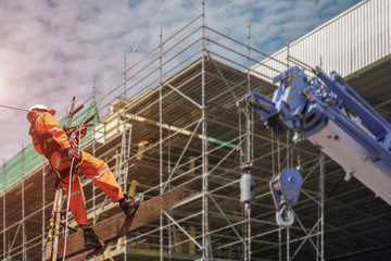 Fototapeta premium Rope access Safety sprinkling worker on high with scaffolding wear dresses and safety man with harness safety concept in site construction building with copy space on staging background.