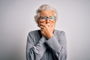 Senior beautiful grey-haired woman wearing casual sweater and glasses over white background shocked...