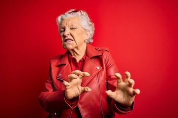 Senior beautiful grey-haired woman wearing casual red jacket and sunglasses disgusted expression, displeased and fearful doing disgust face because aversion reaction. With hands raised