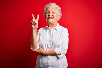 Senior beautiful woman wearing elegant shirt standing over isolated red background smiling with...