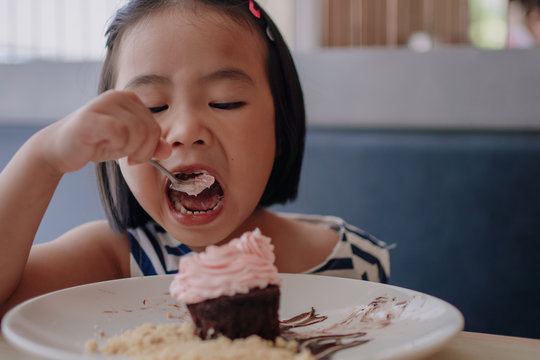 A girl eating happily with a strawberry whipped cream. 4 year old daughter Celebrating a birthday with a chocolate lava dessert