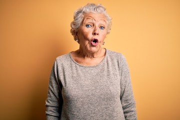 Senior beautiful woman wearing casual t-shirt standing over isolated yellow background afraid and...