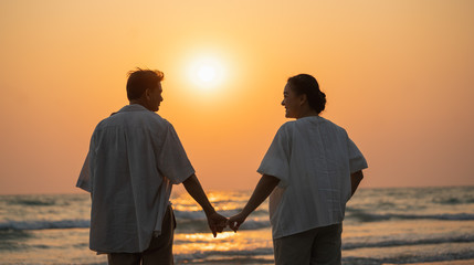 Elderly couple moments of relaxation with a happy picture impression. Tour. Portrait of a middle-aged man standing holding hands by the sea in the evening.