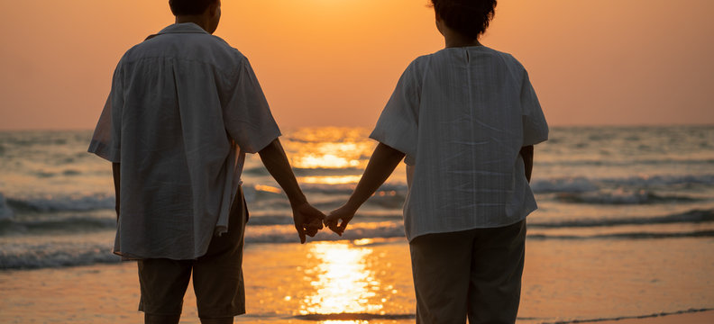 Elderly couple moments of relaxation with a happy picture impression. Tour. Portrait of a middle-aged man standing holding hands by the sea in the evening.
