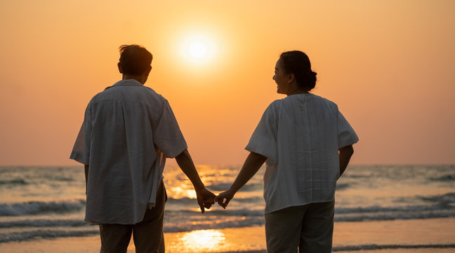 Elderly couple moments of relaxation with a happy picture impression. Tour. Portrait of a middle-aged man standing holding hands by the sea in the evening.