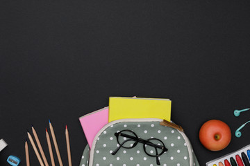 Creative flatlay of education green table with backpack, student books, colorful crayon, eye glasses, empty space on blackboard background, Concept of education and back to school