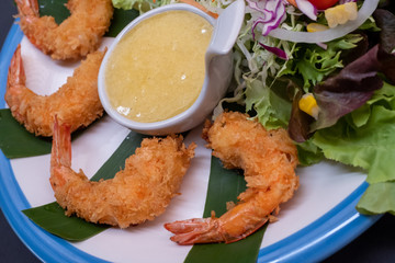 Shrimp tempura and salad of fresh vegetables close-up on a plate on black background. horizontal view from above