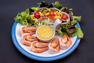Shrimpand salad of fresh vegetables close-up on a plate on black background. horizontal view from above