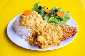 Curry fried Batter Fish with rice on plate over yellow background. Top view, flat lay.