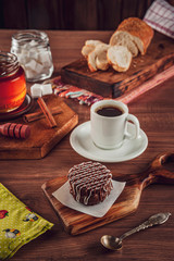 Honey cookie chocolate covered on the wooden table with coffee and sliced bread - pão de mel