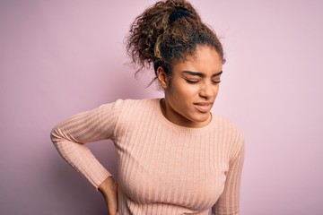 Young beautiful african american girl wearing casual sweater standing over pink background Suffering of backache, touching back with hand, muscular pain