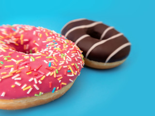two doughnuts pink and chocolate on a blue background close up in perspective