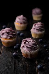 Blueberry cupcakes and berries on a black wooden background.