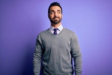 Handsome businessman with beard wearing casual tie standing over purple background smiling looking to the side and staring away thinking.