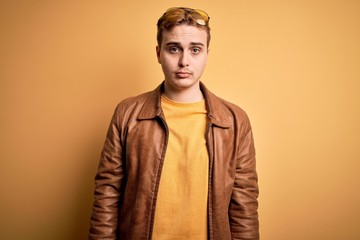 Obraz premium Young handsome redhead man wearing casual leather jacket over isolated yellow background depressed and worry for distress, crying angry and afraid. Sad expression.