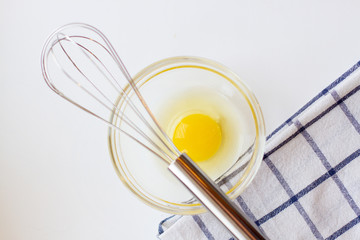 egg yolk in a glass bowl and towel on a white background.