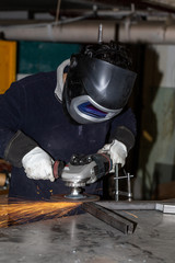 Factory worker working with a grinder causing heaving sparks