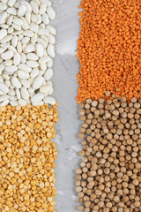Assortment of beans and lentils on grey background. Vertical Chickpeas, pea and beans scattered. zero waste concept.