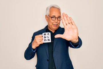 Middle age senior grey-haired man drinking a coffee on best dad cup over isolated background with open hand doing stop sign with serious and confident expression, defense gesture