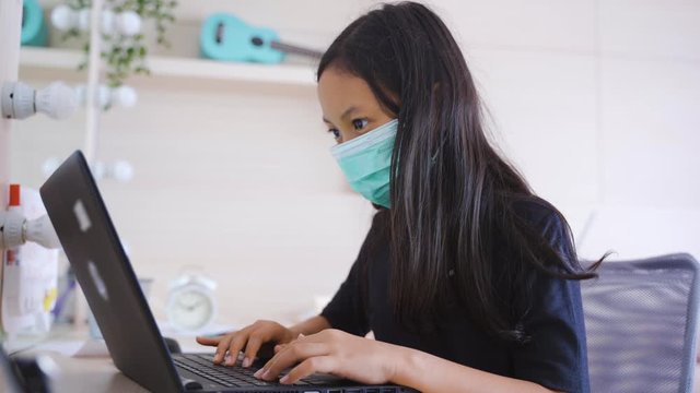 Little girl wearing a mask and doing online lesson
